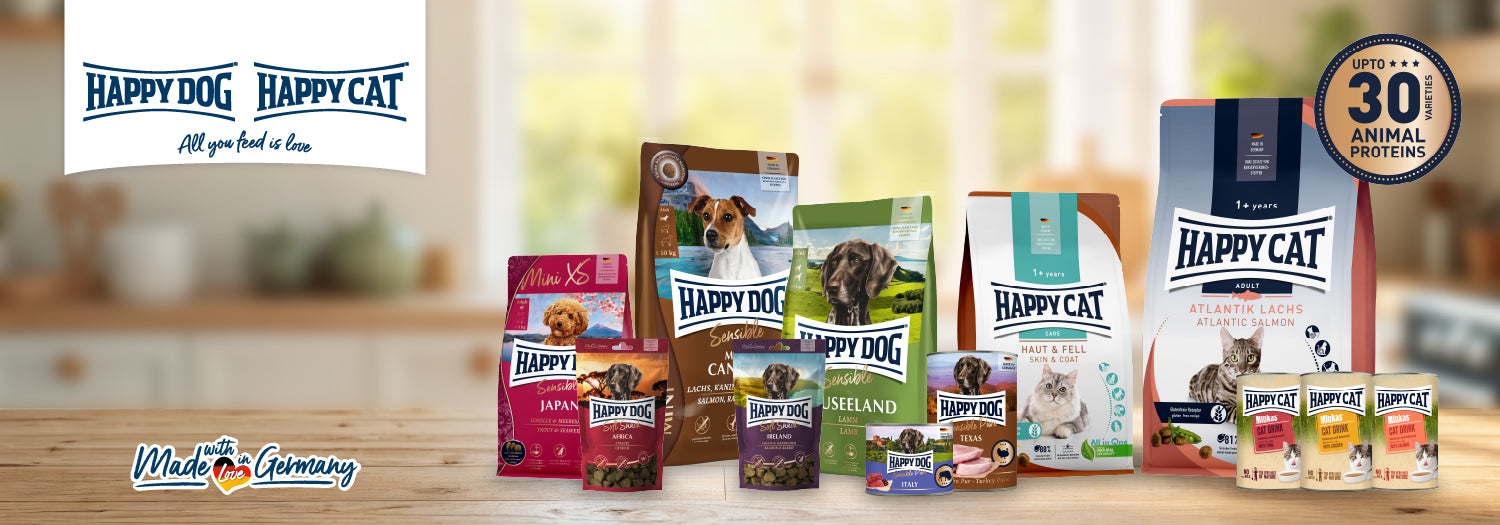 Happy Dog and Happy Cat pet food products on a wooden surface with blurred background